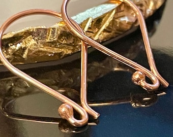 May include: A pair of rose gold earring hooks. The hooks are made of metal and have a smooth, polished finish.