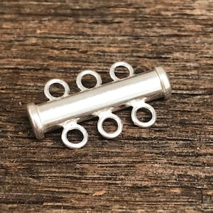 May include: Silver-toned metal four-strand connector for jewelry making. The connector has four loops on each end, allowing for multiple strands of beads or chain to be attached.