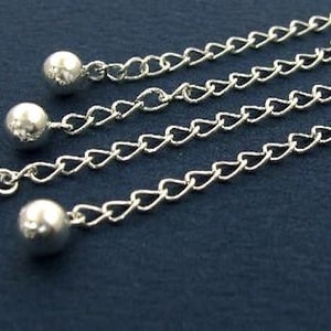 May include: Four silver chains with round silver beads at the end. The chains are arranged in a fan shape on a dark blue background.