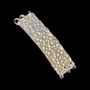 May include: A silver hammered metal bar with three loops on each end. The bar is textured with a hammered finish.