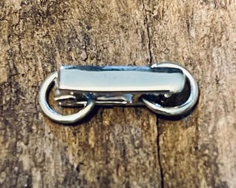 May include: A silver metal clasp with two rings. The clasp is designed to connect two pieces of jewelry or other items.