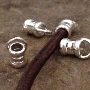 May include: Four silver metal cord ends with a loop on each end. The cord ends are designed to be used with leather cord.