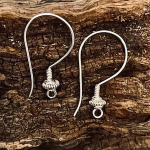 May include: Two silver earring hooks with a small, decorative, twisted metal ball at the end of each hook.
