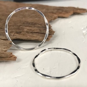 May include: Two silver hammered rings, one larger than the other, on a white surface.