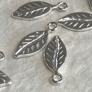 May include: Silver leaf charms with a textured design and a jump ring for attaching to jewelry or crafts.