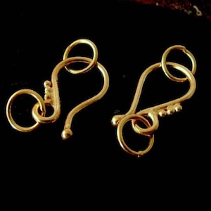 May include: Two gold-toned metal clasps with a hook and loop design. The clasps are commonly used for jewelry making.