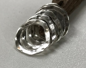 Peut inclure: Une pile d'anneaux en argent avec une texture martelée. Les anneaux sont empilés les uns sur les autres et sont tous de la même taille.