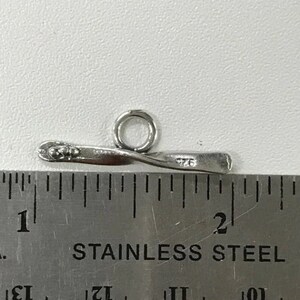 May include: Silver-toned metal toggle clasp with a twisted bar and a round ring. The clasp measures approximately 1 inch in length.