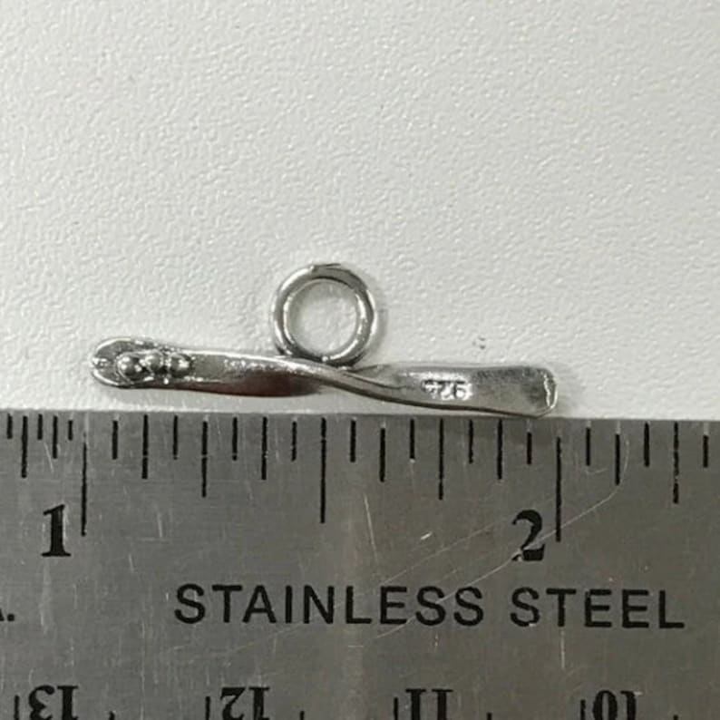 May include: Silver-toned metal toggle clasp with a twisted bar and a round ring. The clasp measures approximately 1 inch in length.