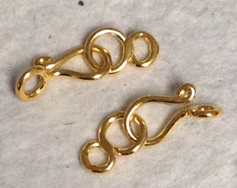 May include: Two gold-toned metal clasps with a looped design. Each clasp has a hook and a loop for attaching to a necklace or bracelet.