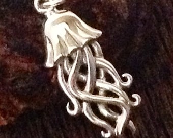 May include: A silver charm in the shape of a jellyfish with a bell-shaped top and long, flowing tentacles.