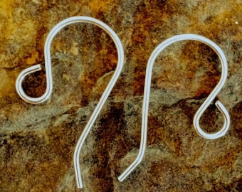 May include: Two silver earring hooks, also known as French hooks, are shown against a brown, textured background.