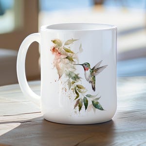 May include: White ceramic mug with a watercolor illustration of a hummingbird in flight, surrounded by green leaves and pink flowers.