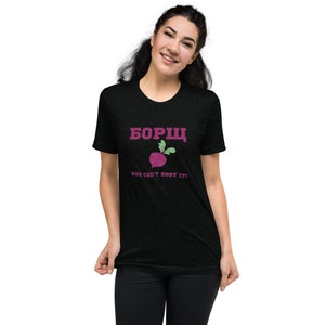 Peut inclure: Un t-shirt noir avec une betterave rose et le texte "Bорщ you can't beet it!" en rose.