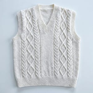 May include: Cream cable knit sweater vest with a V-neck. The sleeveless vest has a textured cable knit design on the front and back. Ribbed hem and neckline. A classic, versatile layering piece. The measurements are in centimetres.