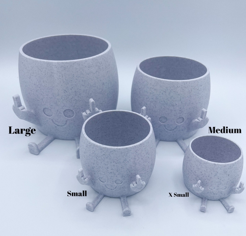 K&ouml;nnte beinhalten: Vier graue Keramik-Blument&ouml;pfe mit einer gesprenkelten Oberfl&auml;che, geformt wie eine Comicfigur mit Armen und Beinen. Die T&ouml;pfe sind mit "Large", "Medium", "Small" und "X Small" beschriftet.