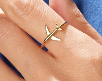 Op de afbeelding: Gouden vliegtuigring. Het vliegtuig is een simpel ontwerp met een dunne band. De ring zit aan een vinger.
