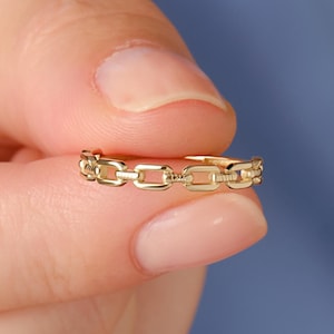 May include: A gold chain ring with a simple design. The ring is made of multiple connected links.