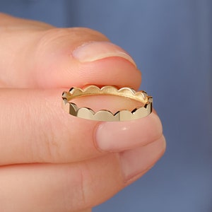 May include: A gold ring with a scalloped edge.