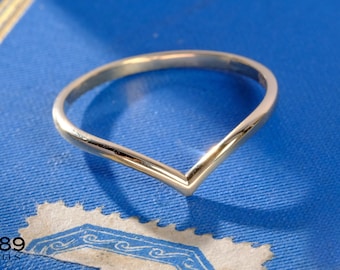 May include: A polished gold-tone V-shaped chevron ring with a smooth, rounded band. The ring features a pointed center design and a reflective metallic finish. The text 1789 JEWELS is visible in the bottom left corner of the image.