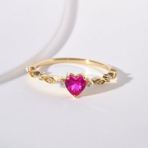 May include: A gold ring with a pink heart-shaped gemstone and small clear stones on the band.