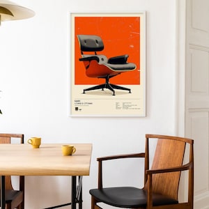 May include: A framed poster featuring a mid-century modern chair design against an orange background. The chair is black and red, with a black base. The poster is displayed on a white wall in a dining room setting.