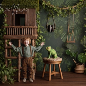 May include: A young child stands in a jungle-themed setting with a wooden treehouse and a green chameleon on a stool. The background features lush greenery and a swing, creating a playful and adventurous atmosphere.