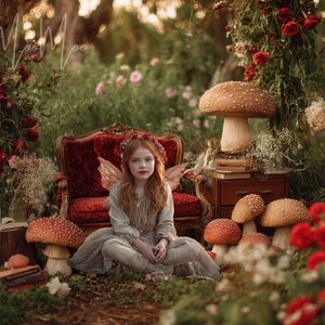 May include: A young person with red hair and fairy wings sits in a whimsical forest scene. The scene includes a red velvet chair, mushrooms, books, and red and white flowers. The overall theme is fantasy and nature.