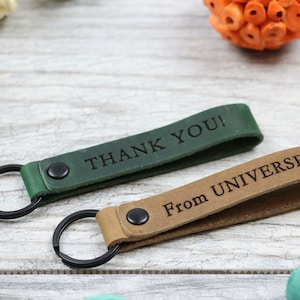 May include: Two leather keychains with metal rings. One is green and says "THANK YOU!" The other is brown and says "From UNIVERSE".