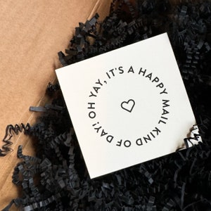 Könnte beinhalten: Eine weiße Karte mit schwarzem Text, der "Oh yay, es ist eine Art glücklicher Posttag." lautet, mit einem kleinen Herzen in der Mitte des Kreises.