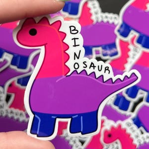 May include: A sticker of a pink, purple, and blue dinosaur with the text "BI-NOSAUR" on it.