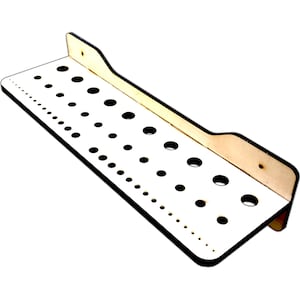 May include: A white wooden wall-mounted tool organizer with a black border and multiple circular holes for storing tools.