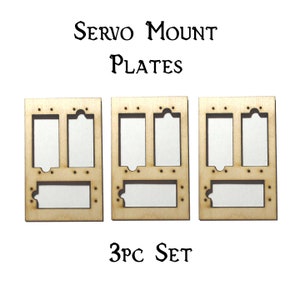 May include: A set of three wooden servo mount plates. Each plate has three rectangular cutouts and a larger rectangular cutout at the bottom. The plates are labeled "SERVO MOUNT PLATES" and "3PC SET".