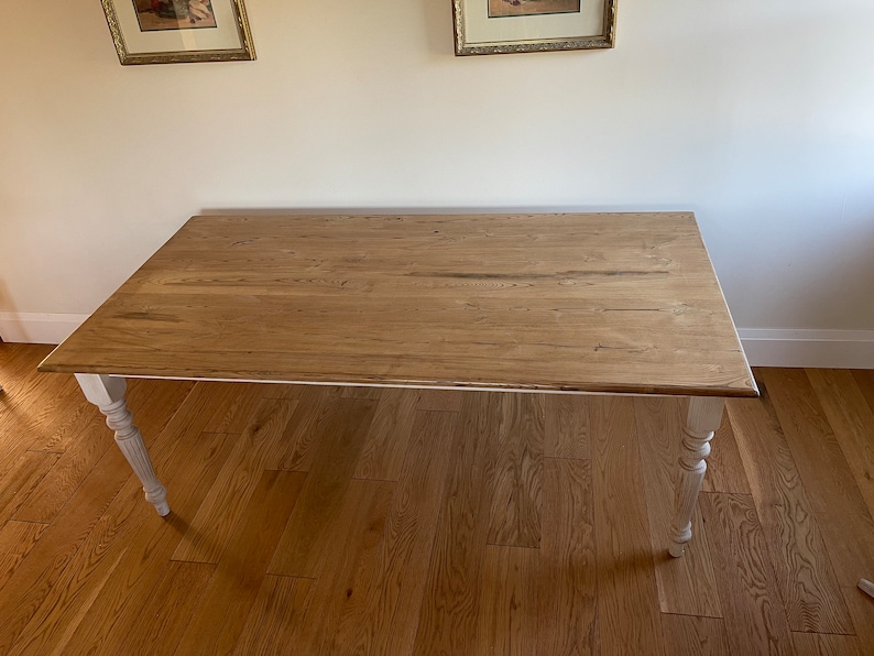 May include: A wooden table with a natural wood top and white painted legs. The table has a simple design and is perfect for a dining room or kitchen.