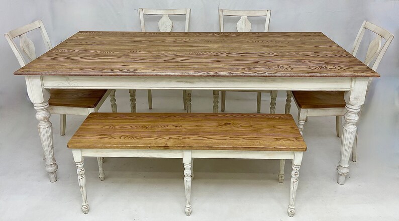 May include: A white farmhouse style dining table with a wood top and four chairs. A matching bench is in front of the table.