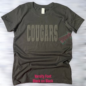 May include: Black t-shirt with the word "COUGARS" in a raised, varsity-style font. The text is black on black.