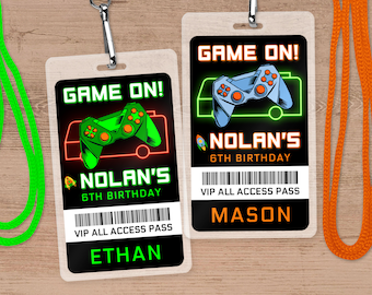 May include: Two printable 'Game On!' birthday party badges featuring a neon green and blue video game controller graphic, the text 'Game On!' and 'Nolan's 6th Birthday', a barcode, and the text 'VIP All Access Pass'. One badge says 'Ethan' and the other says 'Mason'.