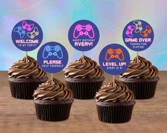 May include: Six chocolate cupcakes with blue and neon pink and orange gamer controller themed cupcake toppers. The toppers say "Welcome to my party!" "Please help yourself" "Happy Birthday Avery!" "Game Over Thanks for Playing" "Level Up! Avery is 9!"