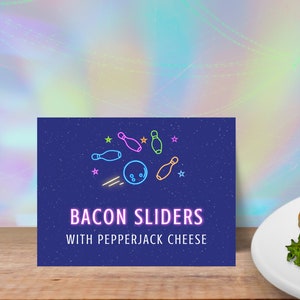以下が含まれることがあります： ボーリングのボールとピンが描かれた青い看板。看板には「Bacon Sliders with Pepperjack Cheese」と書かれています。