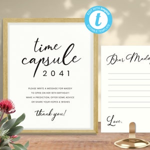 Może przedstawiać: Biały znak z czarnym tekstem, na którym widnieje napis "time capsule 2041". Znak zawiera również instrukcje dotyczące pisania wiadomości dla Maddy, którą ma otworzyć na swoje 18. urodziny. Drugi biały znak z czarnym tekstem brzmi "Droga Maddy" i ma linie do pisania wiadomości. Znaki znajdują się na drewnianej powierzchni.