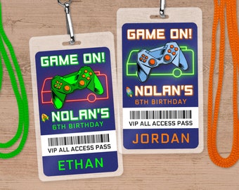 May include: Two blue and purple game-themed party favour badges with a green and blue video game controller graphic, the text "GAME ON!" and "NOLAN'S 6TH BIRTHDAY", and a barcode with the text "VIP ALL ACCESS PASS". The badges have the names "ETHAN" and "JORDAN" printed below the barcode.