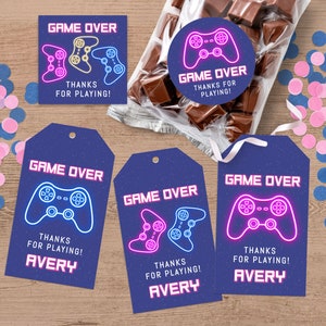 Peut inclure: Quatre étiquettes de faveur bleues et blanches avec le texte "Game Over" et un graphisme de manette de jeu vidéo rose et bleu néon. Les étiquettes comprennent également le texte "Merci d'avoir joué !" et le nom "Avery".
