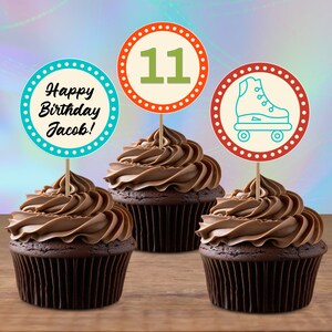 Peut inclure: Trois cupcakes au chocolat avec des décorations de cupcakes colorées. Les décorations présentent un cercle bleu et turquoise avec le texte "Happy Birthday Jacob!" un cercle rouge et orange avec le numéro "11" en vert, et un cercle rouge et orange avec un patin à roulettes bleu.
