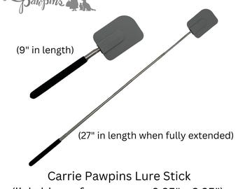 May include: Two grey silicone spatulas with black handles, one measuring 9 inches in length and the other extending to 27 inches. The text Carrie Pawpins Lure Stick and lickable surface approx. 3.25 inches by 2.25 inches is visible on the image.