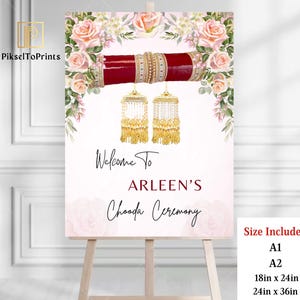 May include: A welcome sign for an Indian wedding ceremony with pink floral designs and gold and red jewelry. The sign reads "Welcome to Arleen's Chooda Ceremony". The sign is available in two sizes: 18 inches by 24 inches and 24 inches by 36 inches.