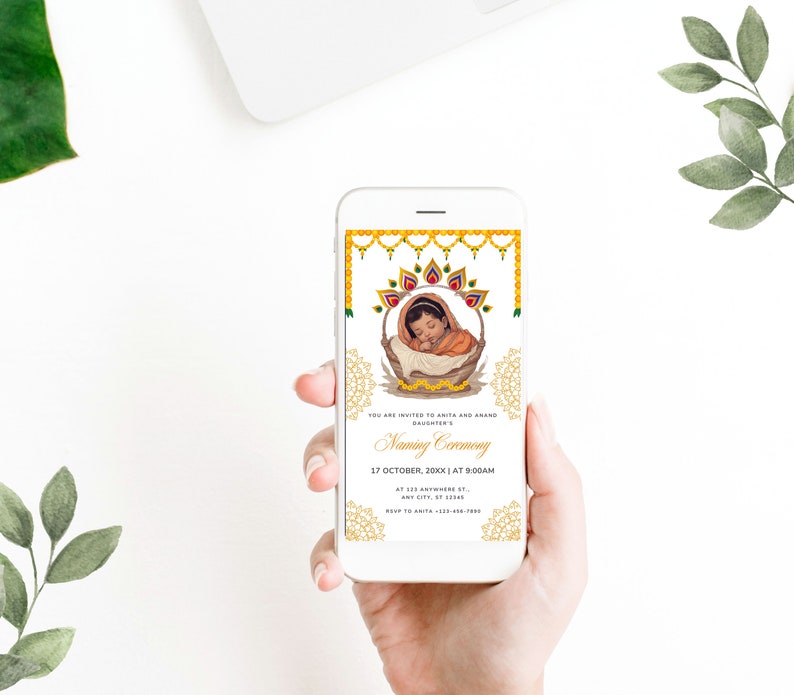 May include: A mobile phone displaying a digital invitation for a baby naming ceremony. The invitation features a golden design with a picture of a baby in a basket. The text on the invitation reads "You are invited to Amit and Amand's daughter's Naming Ceremony 17 October, 20XX | at 9:00 AM at 123 Anywhere St. Any City, ST"