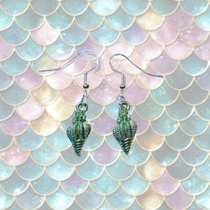 May include: A pair of silver earrings with green seashell charms. The seashells are detailed and have a textured surface.