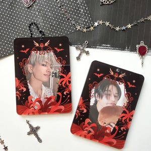 May include: Two rectangular black photo charms with red floral designs and images of people. The charms have a decorative border and are adorned with bats. Additional charms include a heart, a cross, and a star chain.