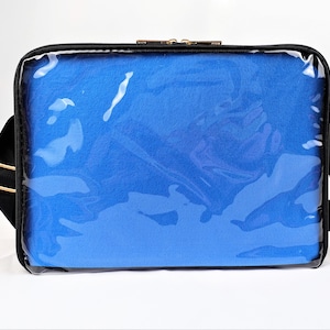 K&ouml;nnte beinhalten: Schwarze Laptoptasche mit einer durchsichtigen Frontplatte aus Kunststoff und einem blauen gepolsterten Innenraum. Die Tasche hat einen Schultergurt.