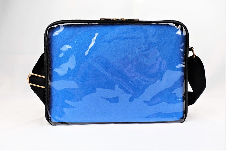 K&ouml;nnte beinhalten: Schwarze Laptoptasche mit einer durchsichtigen Frontplatte aus Kunststoff und einem blauen gepolsterten Innenraum. Die Tasche hat einen Schultergurt.